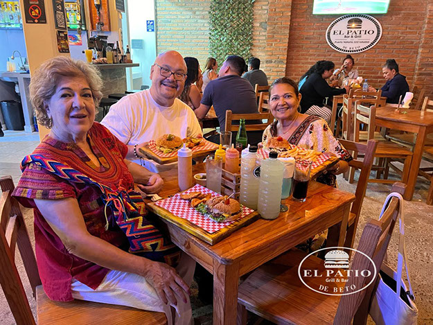 Clientes en una mesa con hamburguesas y bebidas en El Patio de Beto